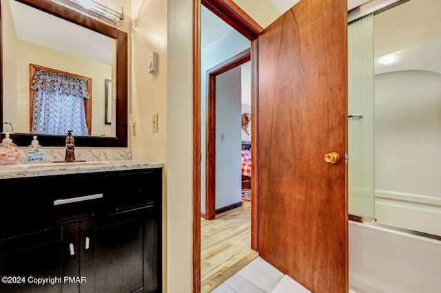 bathroom featuring combined bath / shower with glass door, vanity, and wood finished floors