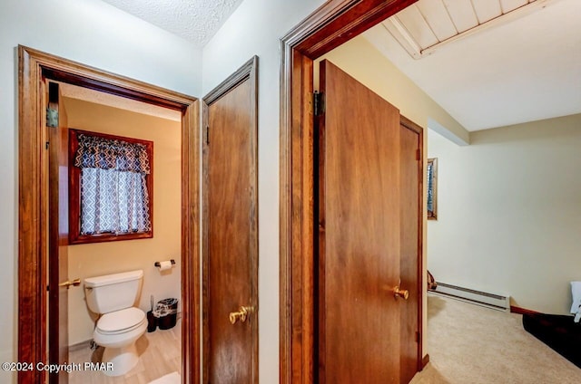 corridor with carpet flooring, a textured ceiling, and a baseboard radiator