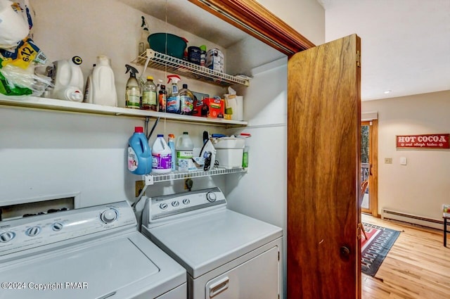 clothes washing area with light wood finished floors, laundry area, baseboard heating, and separate washer and dryer