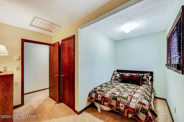 carpeted bedroom with baseboards and a textured ceiling