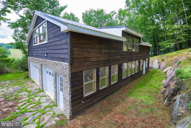 view of side of property with a garage and metal roof