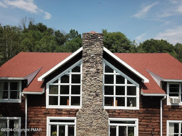 exterior space with roof with shingles, a chimney, and cooling unit