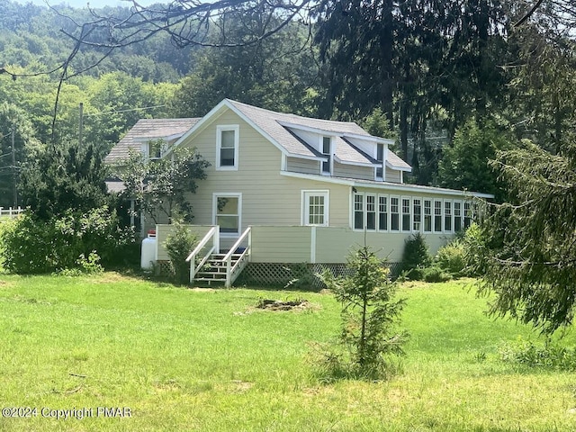 rear view of house featuring a lawn and a view of trees