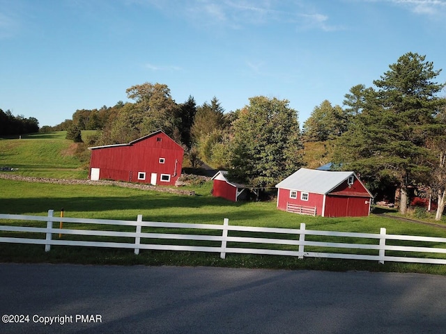 view of yard with a barn, fence, and an outbuilding