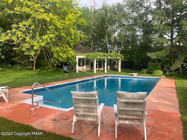 outdoor pool with an outbuilding, an exterior structure, a lawn, and a patio