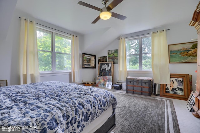 carpeted bedroom featuring multiple windows, vaulted ceiling, and a ceiling fan