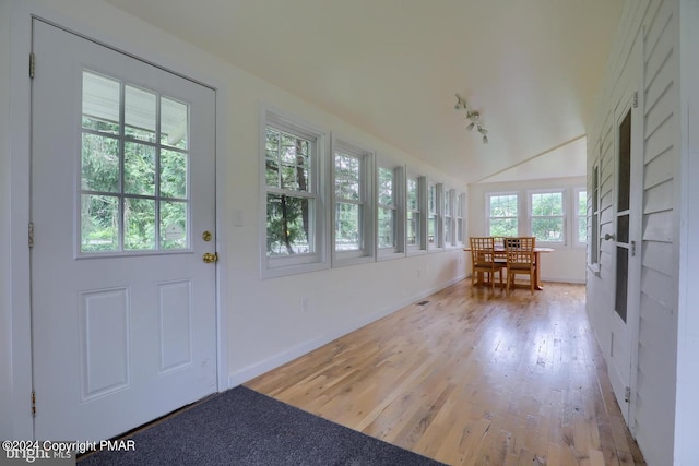 unfurnished sunroom featuring rail lighting and vaulted ceiling