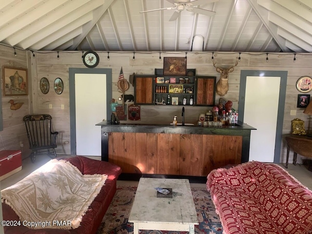 kitchen with lofted ceiling with beams, wood walls, dark countertops, and ceiling fan