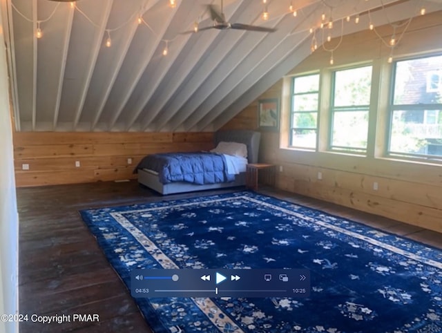 unfurnished bedroom with lofted ceiling, wooden walls, and wood finished floors