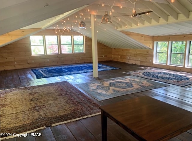 additional living space featuring wood walls, wood-type flooring, and vaulted ceiling