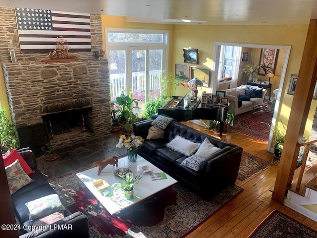 living room featuring plenty of natural light, wood-type flooring, and a stone fireplace