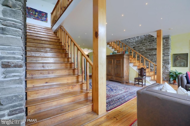 stairs with a towering ceiling and hardwood / wood-style flooring