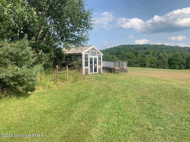 view of yard featuring a forest view, exterior structure, and an outbuilding