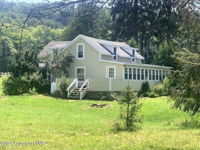 back of house featuring a view of trees and a yard