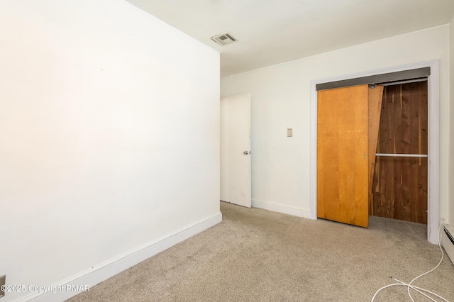 empty room featuring a baseboard radiator and light colored carpet