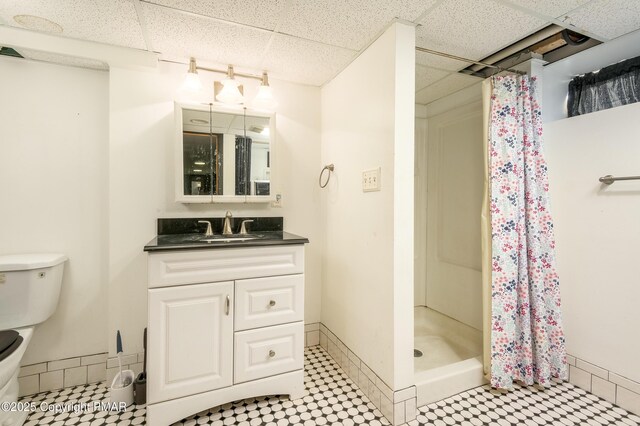 bathroom with vanity, a paneled ceiling, toilet, and walk in shower