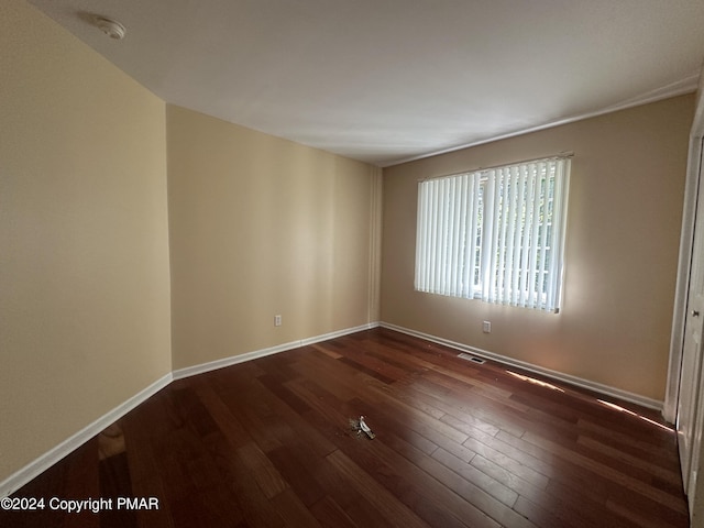 unfurnished room with wood finished floors, visible vents, and baseboards