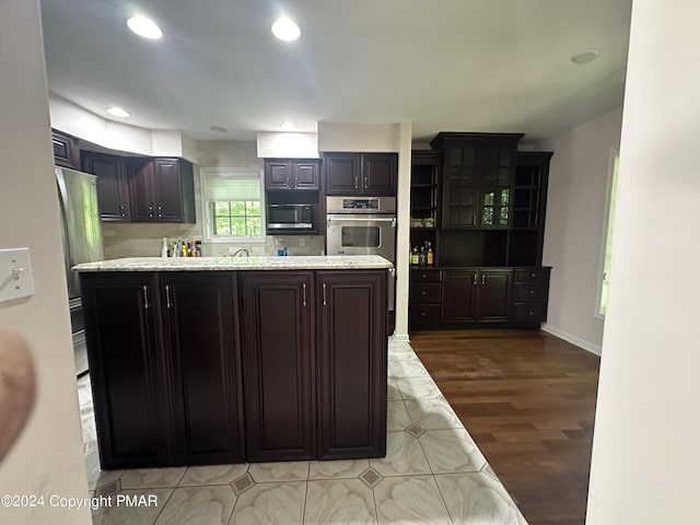 kitchen with a kitchen island, wood finished floors, built in microwave, stainless steel oven, and recessed lighting