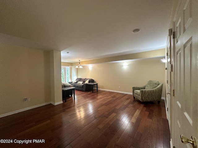 unfurnished room with a chandelier, dark wood-type flooring, and baseboards