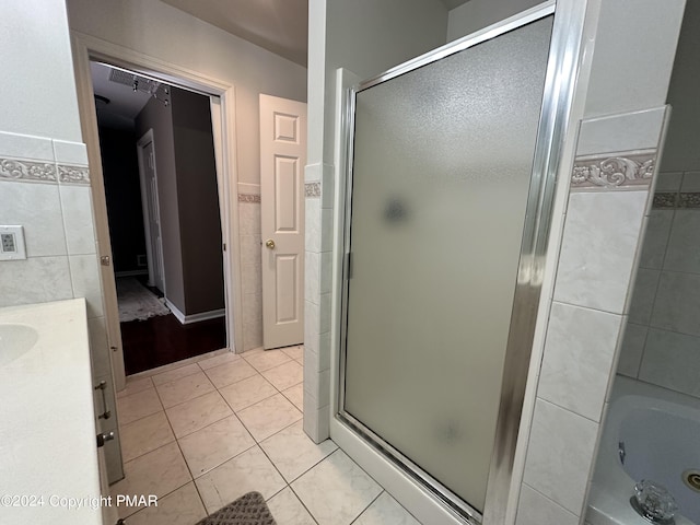 full bath with a whirlpool tub, a stall shower, tile patterned flooring, and tile walls