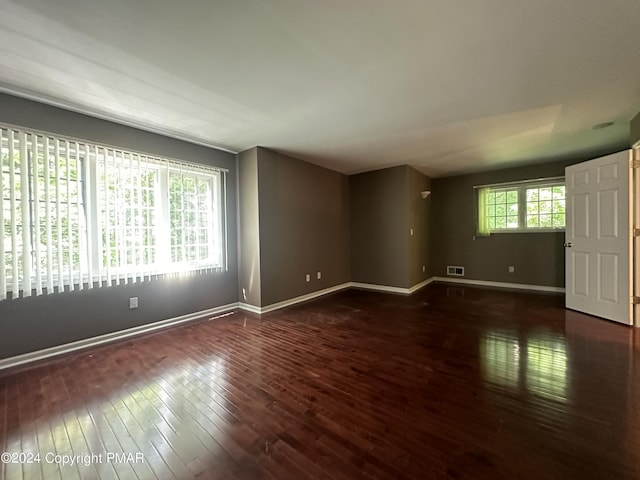 spare room featuring wood-type flooring, visible vents, and baseboards