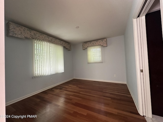 spare room with baseboards and wood finished floors