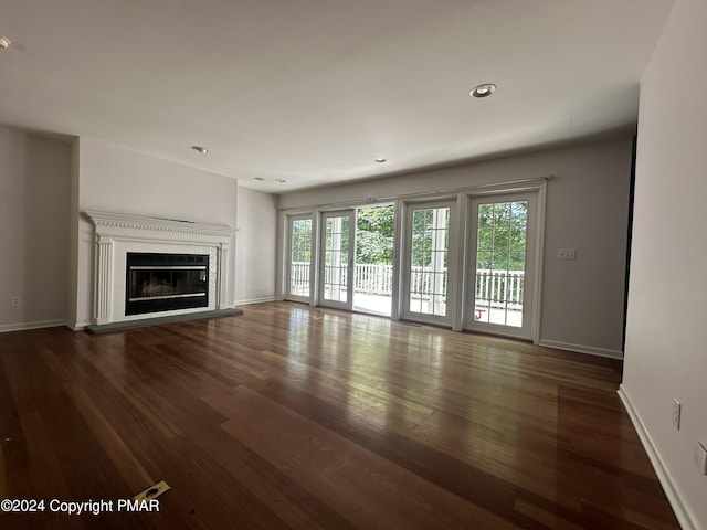 unfurnished living room featuring a glass covered fireplace, recessed lighting, baseboards, and wood finished floors