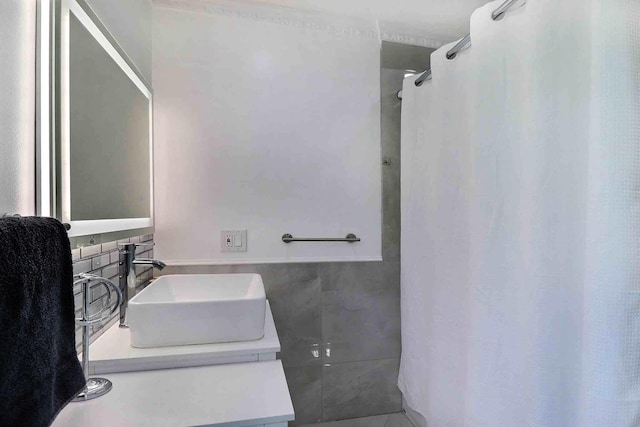 full bath featuring tile walls, vanity, a shower with shower curtain, and a wainscoted wall