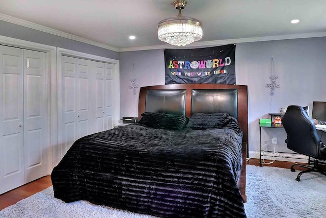 bedroom featuring wood finished floors, multiple closets, crown molding, a chandelier, and recessed lighting