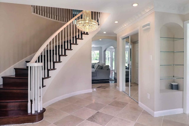 staircase with arched walkways, baseboards, recessed lighting, tile patterned flooring, and ornamental molding