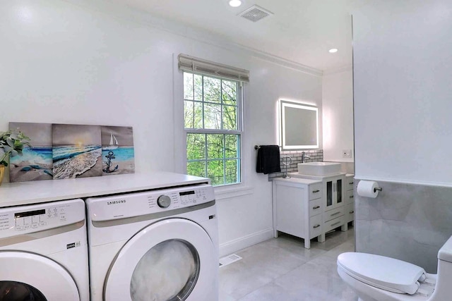 laundry room with washing machine and clothes dryer, light tile patterned floors, and recessed lighting