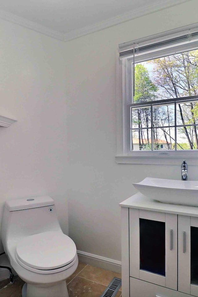 bathroom featuring toilet, ornamental molding, a sink, baseboards, and tile patterned flooring