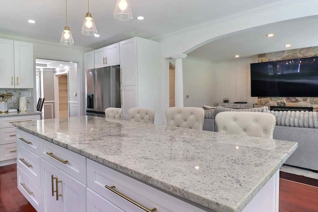 kitchen featuring stainless steel refrigerator with ice dispenser, crown molding, decorative columns, dark wood-style floors, and a center island