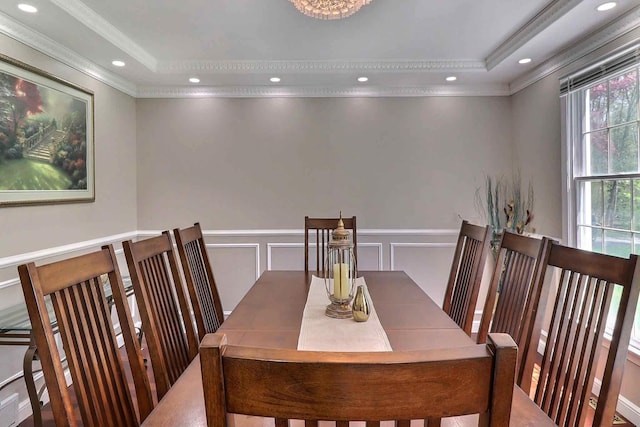 dining room featuring ornamental molding, a raised ceiling, a decorative wall, wainscoting, and recessed lighting