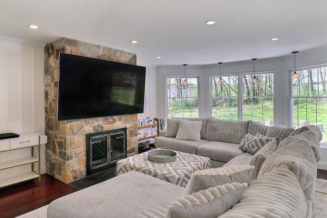 living area with dark wood finished floors, a stone fireplace, and recessed lighting