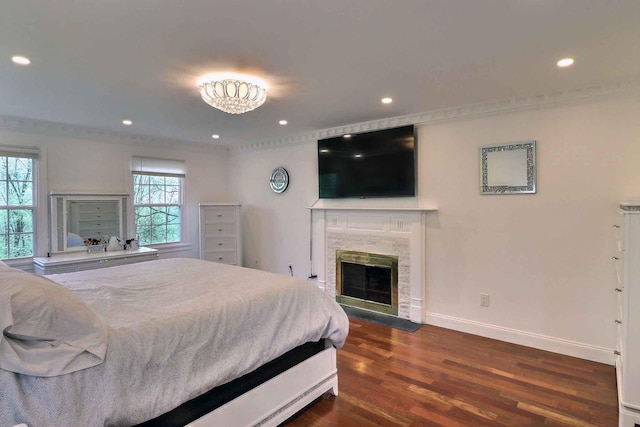 bedroom with dark wood-style floors, baseboards, recessed lighting, ornamental molding, and a premium fireplace
