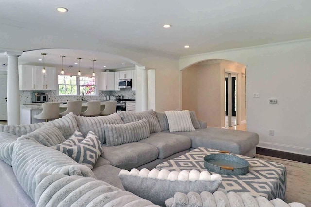 living room with arched walkways, decorative columns, recessed lighting, and wood finished floors