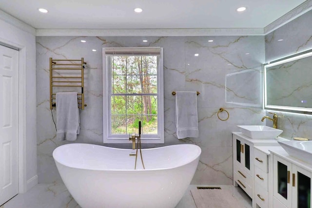 bathroom featuring radiator, marble tiled floors, a soaking tub, double vanity, and recessed lighting
