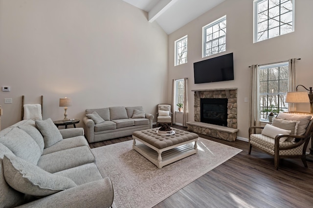 living room with baseboards, dark wood finished floors, a stone fireplace, high vaulted ceiling, and beam ceiling