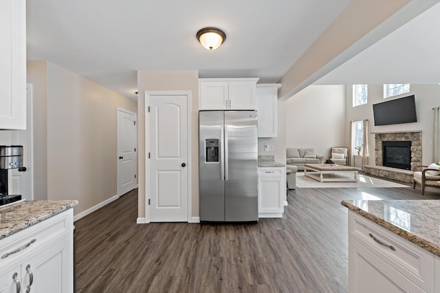 kitchen featuring stainless steel fridge, dark wood finished floors, light stone counters, open floor plan, and white cabinetry