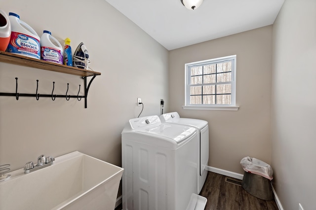 clothes washing area with laundry area, dark wood-type flooring, a sink, baseboards, and washer and clothes dryer