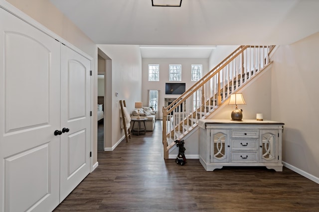 foyer entrance featuring dark wood-style flooring, baseboards, and stairs