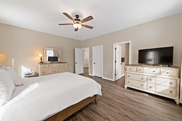 bedroom featuring ceiling fan, ensuite bathroom, visible vents, baseboards, and dark wood finished floors