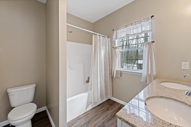 bathroom featuring baseboards, a sink, toilet, and wood finished floors