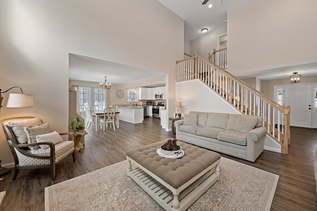 living room featuring baseboards, stairway, a chandelier, and dark wood-type flooring