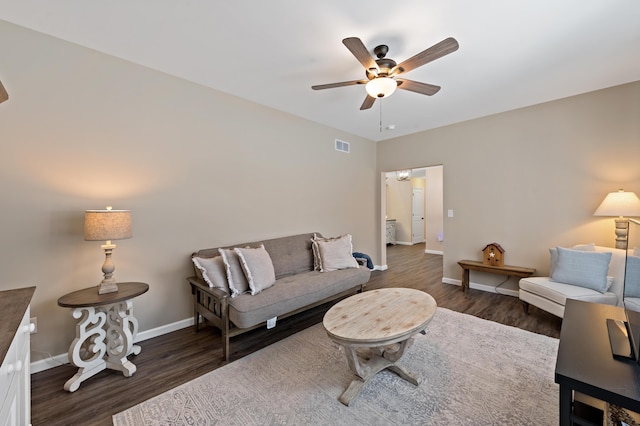 living room with a ceiling fan, visible vents, baseboards, and wood finished floors