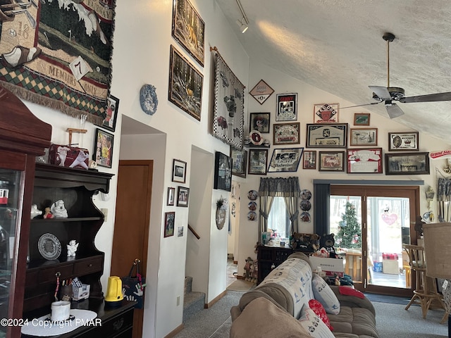 living room with ceiling fan, high vaulted ceiling, a textured ceiling, stairway, and carpet