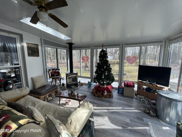 sunroom / solarium with a wood stove, a ceiling fan, and lofted ceiling