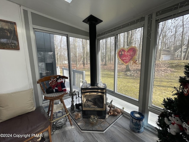 sunroom featuring lofted ceiling, plenty of natural light, and a wood stove