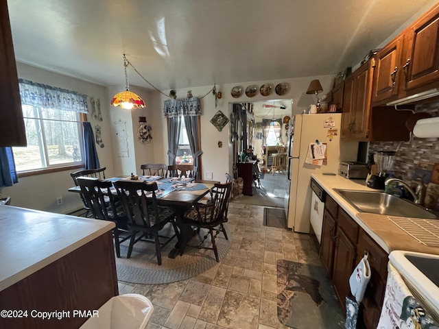 kitchen with white appliances, stone finish floor, decorative light fixtures, light countertops, and a sink